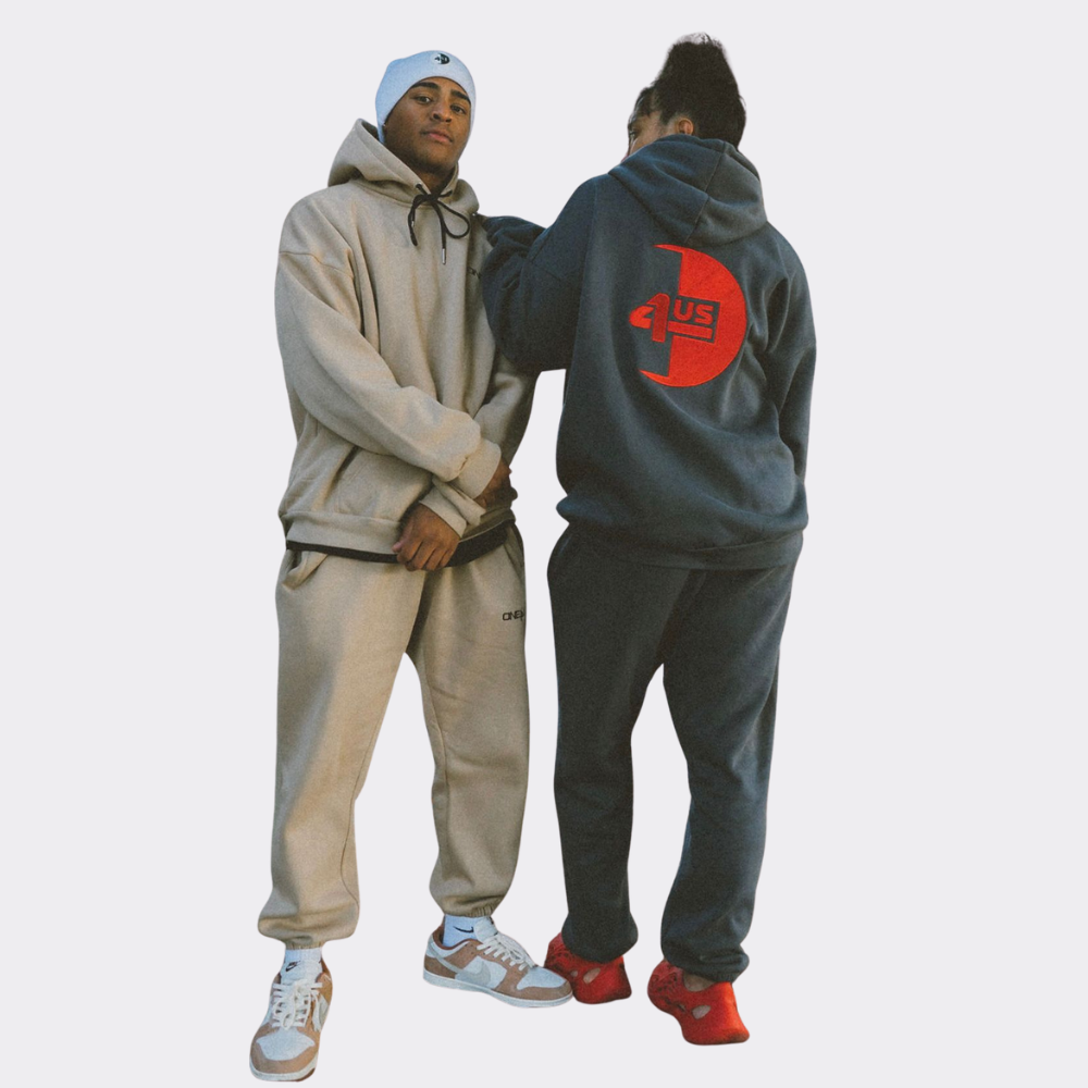 Man and woman wearing matching tracksuits on a plain background