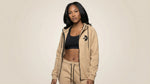 Catalog woman wearing a beige hoodie and black sports bra on a beige background