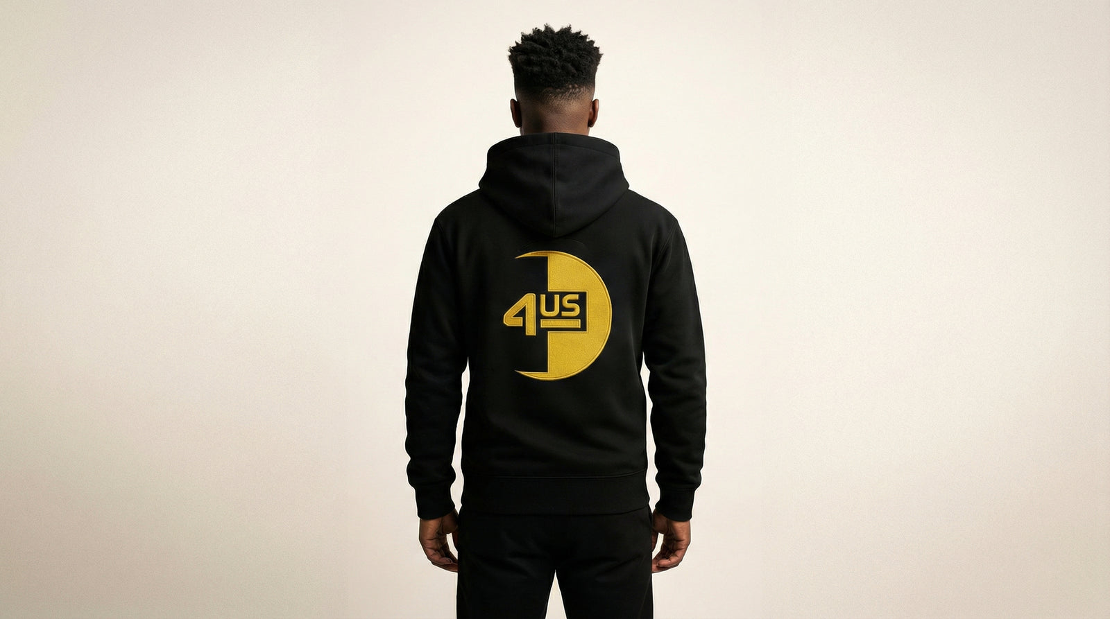 Catalog man wearing a black hoodie with a yellow logo on the back against a beige background