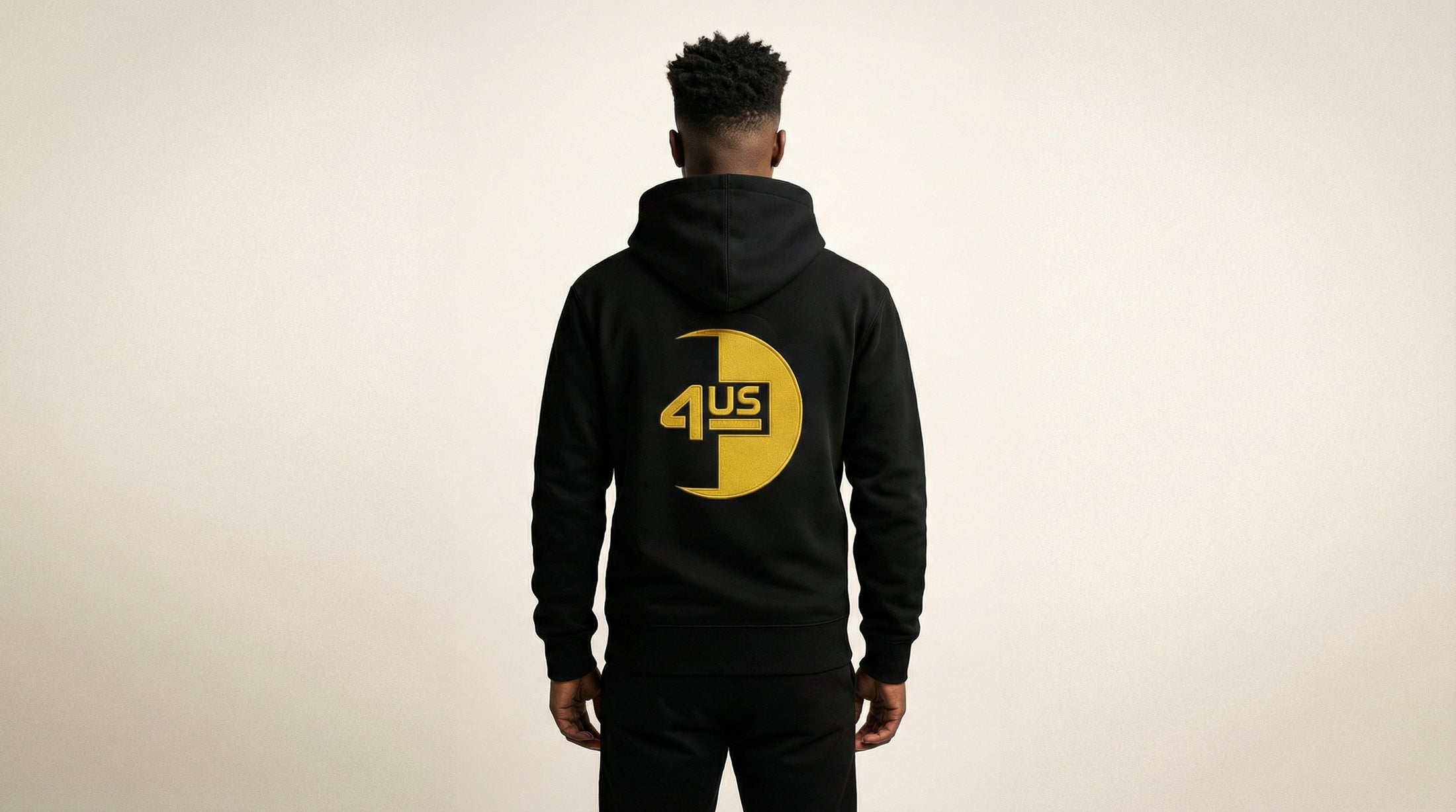 Catalog man wearing a black hoodie with a yellow logo on the back against a beige background