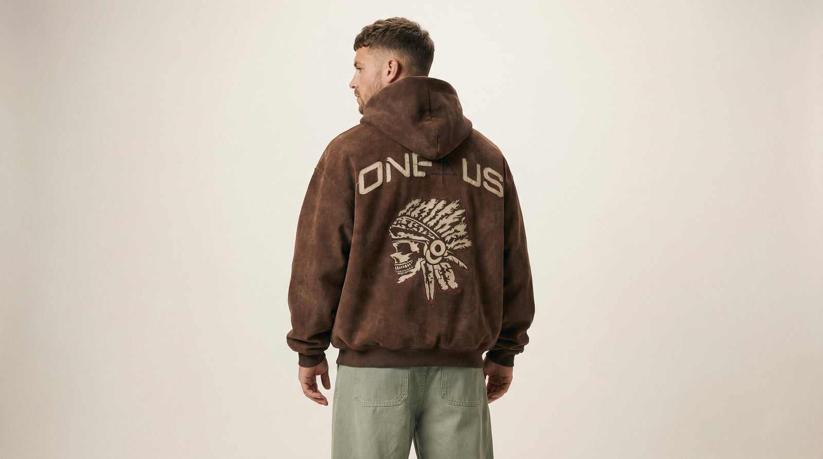 Catalog man wearing a brown hoodie with 'ONE4US' design on the back against a beige background