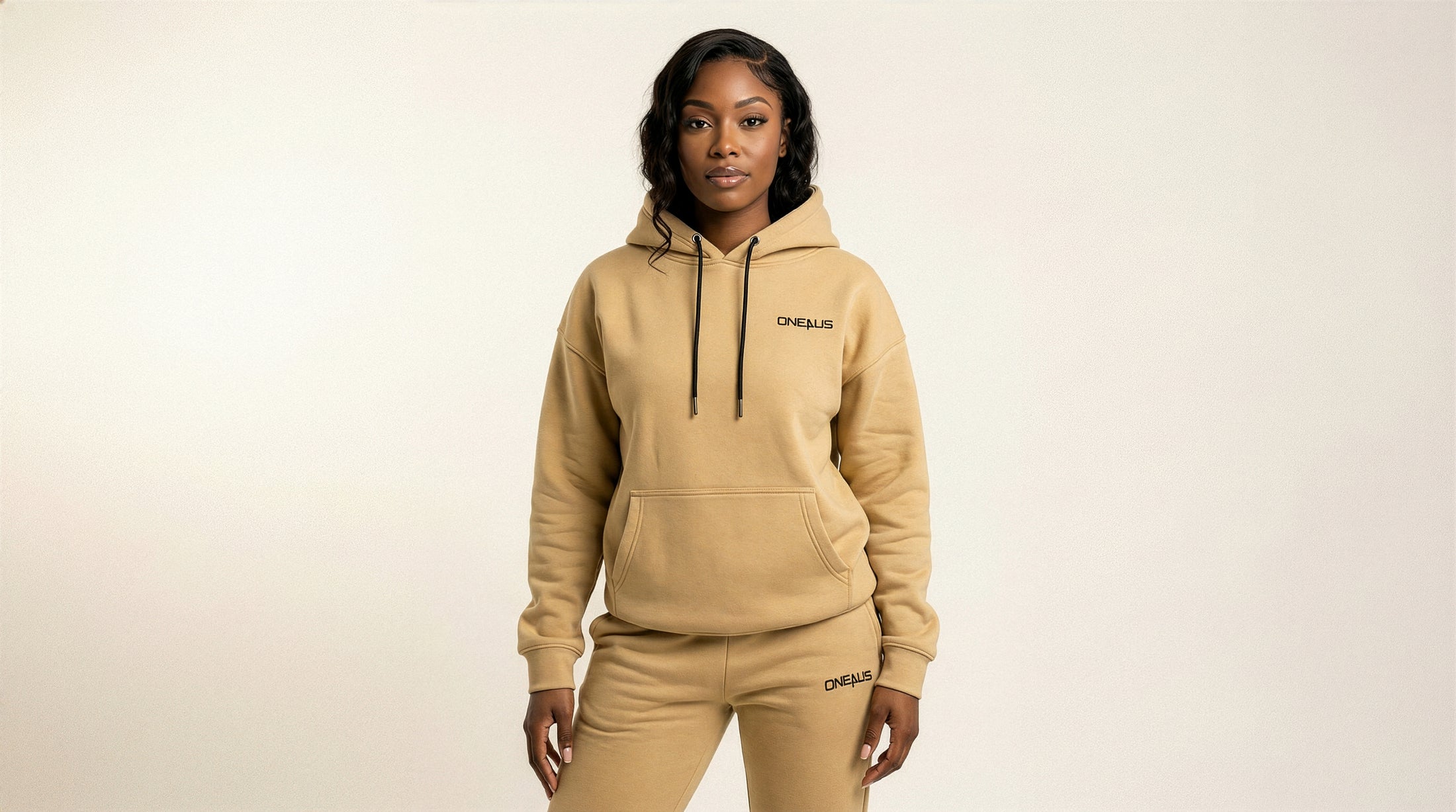 Catalog woman wearing a beige hoodie and pants with a brand logo on a light background