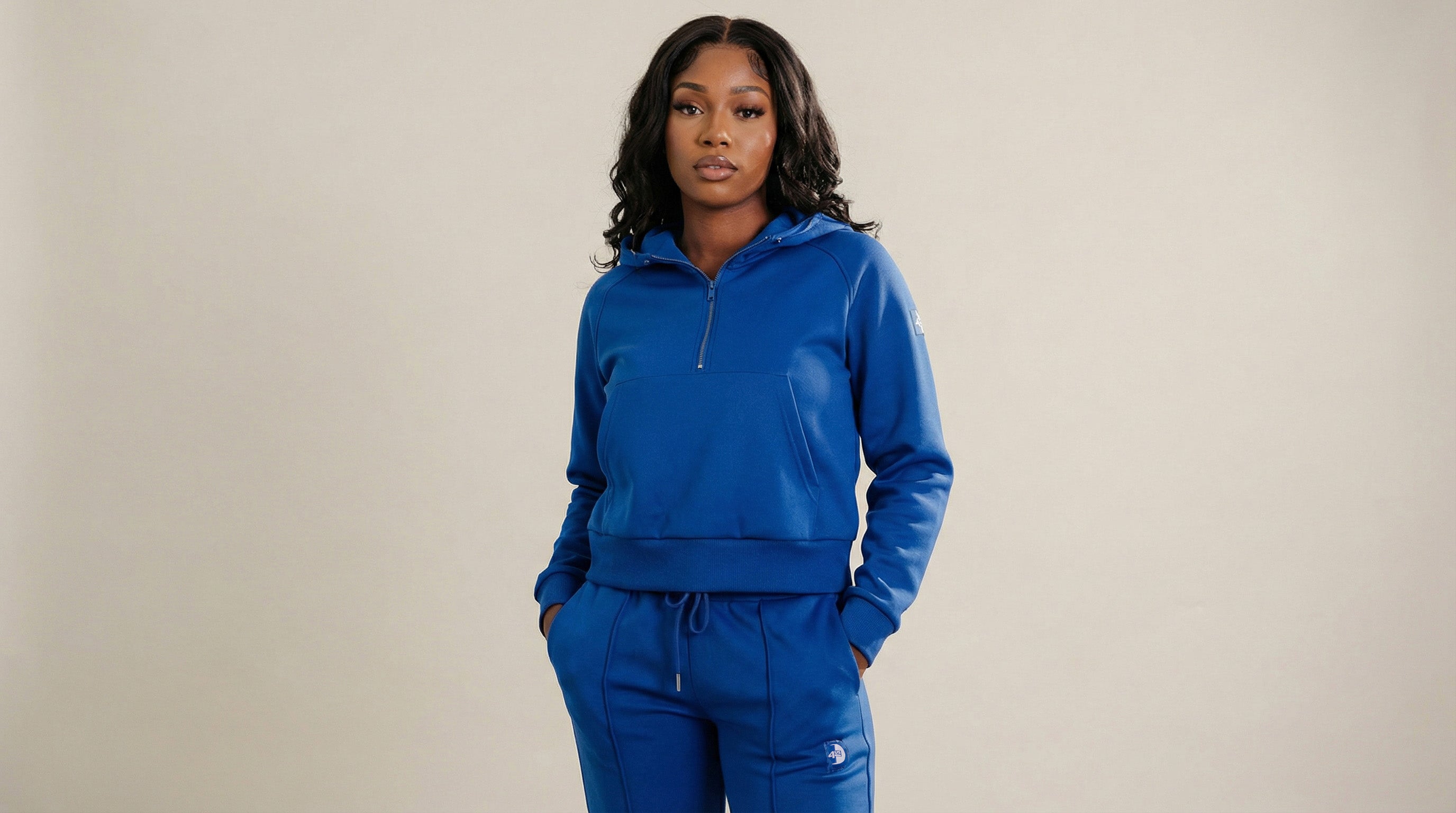 Catalog woman wearing a blue tracksuit against a beige background 